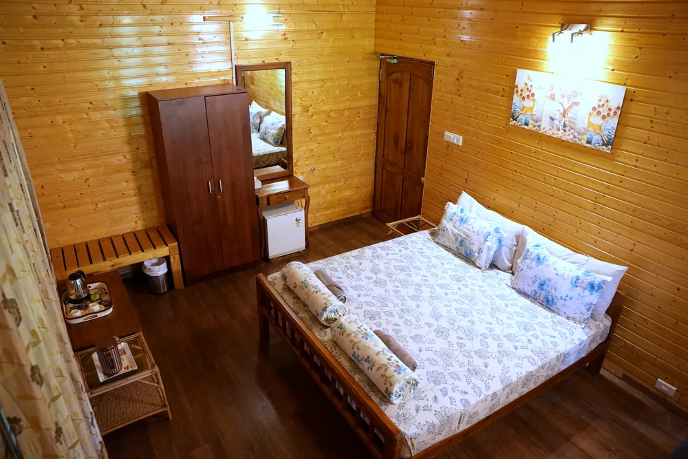 Deluxe Room at Labdhi Resorts with the bed, a wardrobe and a dressing mirror against the timber walls