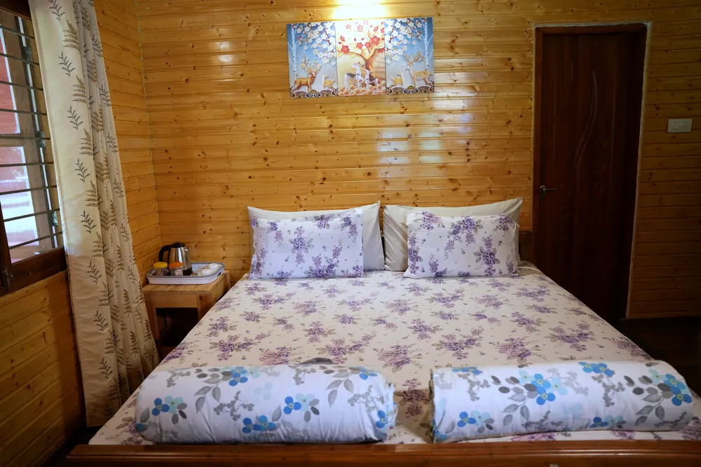 King-size bed made up in floral linen in a Deluxe Room at Labdhi Resorts