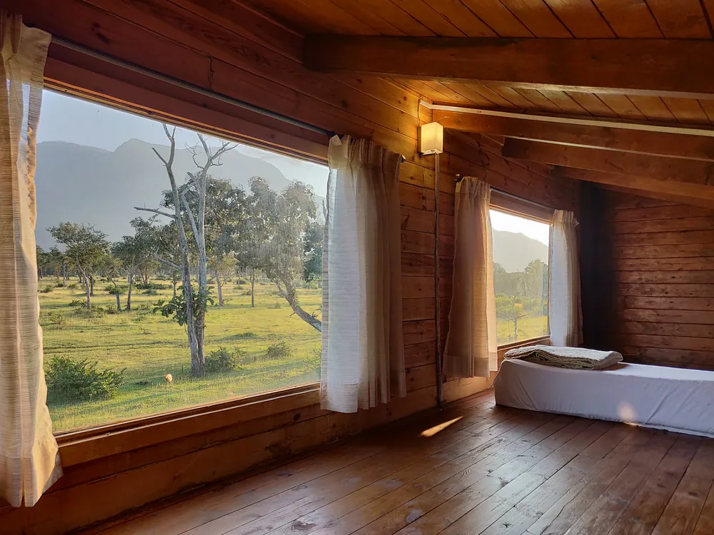 The loft level of the Superior King Room with Loft at Labdhi Resorts, with a wide picture window looking out to the Nilgiri hills